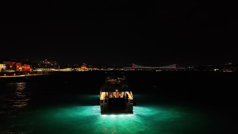 İstanbul köprüsünün ışıkları önünde gece çekilen tekne